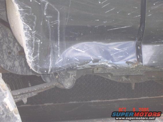 close-up of vehicle's undercarriage, showing suspension and body damage