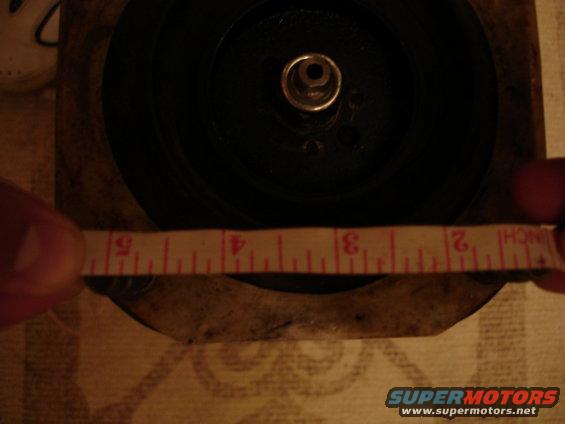 Measuring a round part with a tape measure. The tape shows inches from 1 to 5