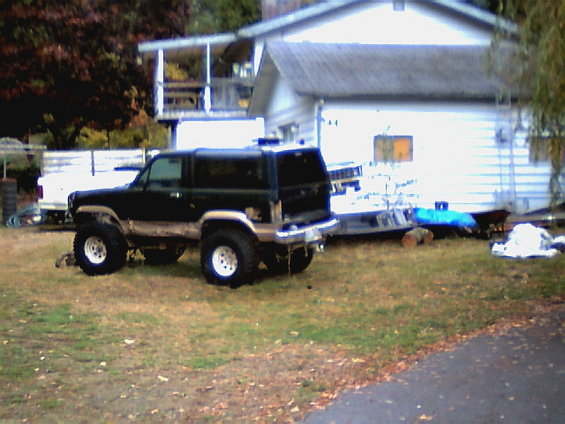 Black lifted SUV with white rims parked on grass