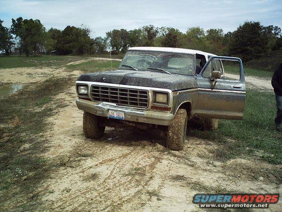 1978 Ford Bronco with open driver's door in muddy field
