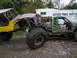 1990 Ford Bronco - Custom off-road vehicles parked outdoors with a trailer in the background.