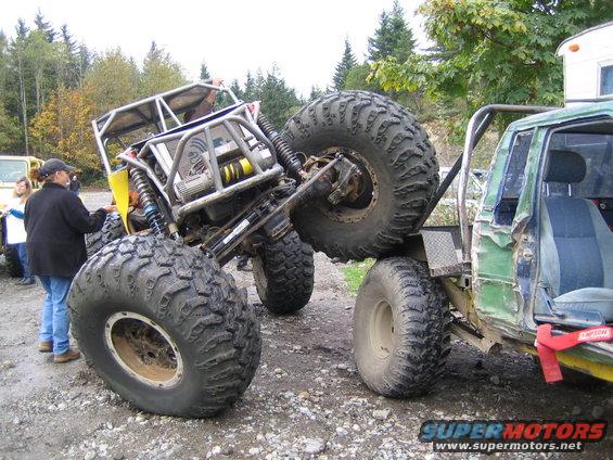Two heavily modified off-road vehicles with large tires on a gravel surface