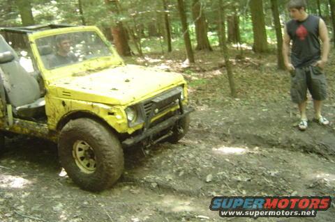Yellow 1987 Suzuki Samurai off-roading in a forest