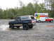 1990 Ford Bronco - A lifted Ford Bronco splashes through a muddy area next to a U-Haul truck.