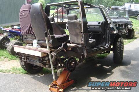 1987 Suzuki Samurai with doors removed, jacked up, and a wooden bed extension. Another vehicle is visible in the background