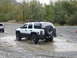 1990 Ford Bronco - This SUV is navigating through a muddy area with trees in the background.