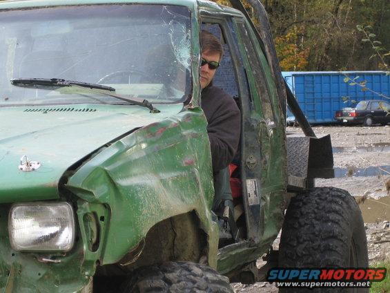 Green off-road vehicle with damaged front end and open door