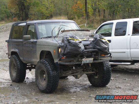 1990 Ford Bronco 3q-front view, dark color, large tires, trash bags on hood