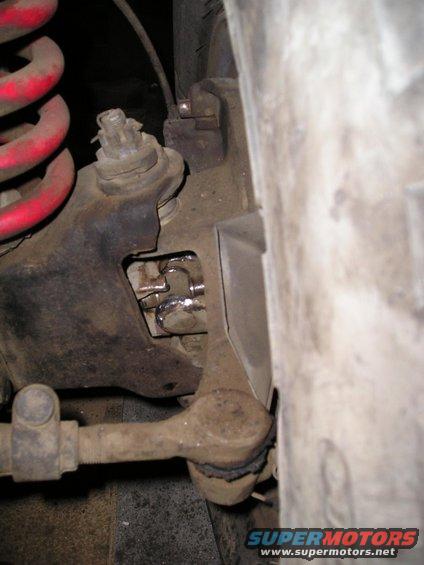 Close-up of a rusty vehicle suspension part with a red coil spring visible