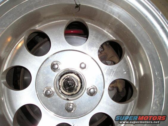 Close-up of a vehicle's wheel hub, brake rotor, and lug nuts