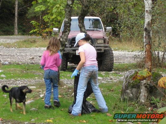 Red SUV with large tires, front view. Two children and a dog are cleaning up