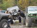 1990 Ford Bronco - A modified Jeep CJ-5, equipped with a winch and custom bumper, is positioned precariously between two other off-road vehicles.