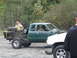 1990 Ford Bronco - A modified green pickup truck sits beside a white truck in an outdoor setting.