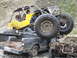 1990 Ford Bronco - An off-road buggy is precariously perched atop a pickup truck, with a driver in the buggy's cockpit.