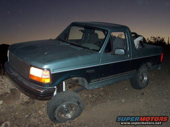 Green two-tone 1996 Ford Bronco with a flat tire on the front passenger side
