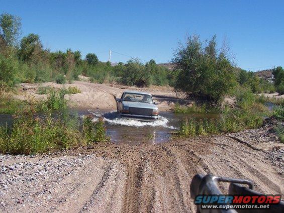 Silver 1992 Ford F-150 driving through a shallow river