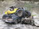 1990 Ford Bronco - A yellow off-road buggy is precariously balanced on top of a pickup truck in a rocky, outdoor setting.