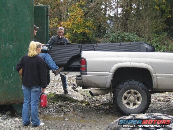 Silver pickup truck rear quarter panel and bed, side view. People loading items