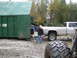 1990 Ford Bronco - People loading a dumpster next to a silver pickup truck. A tire from another vehicle is visible.