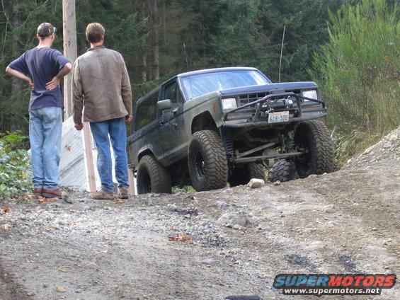 Olive green Ford Bronco with off-road tires and winch on a dirt trail