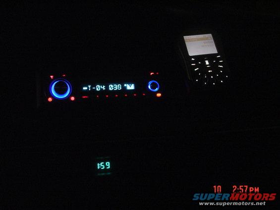 Car stereo and cell phone in a dark interior. Clock shows 1:59