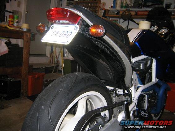 Motorcycle rear with license plate 784-090, black seat cowl with carbon fiber accents, and white wheel