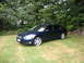2005 Nissan Maxima - A dark blue 2005 Nissan Maxima is parked on a grassy lawn with trees and a stone wall in the background.
