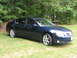 2005 Nissan Maxima - A dark blue 2005 Nissan Maxima is parked on a grassy lawn with trees in the background.