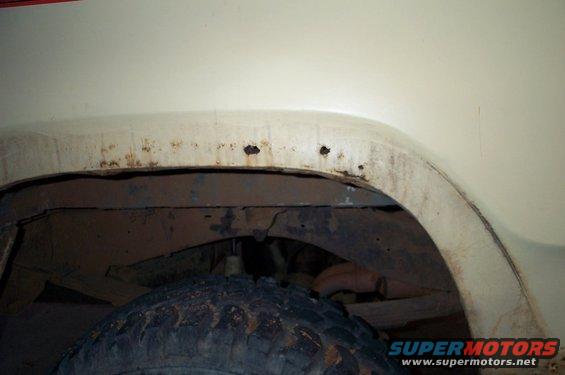 Close-up of a rusty wheel well and tire on a vehicle