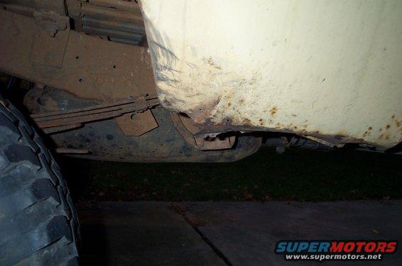 Truck's rusty rear quarter panel and leaf spring suspension