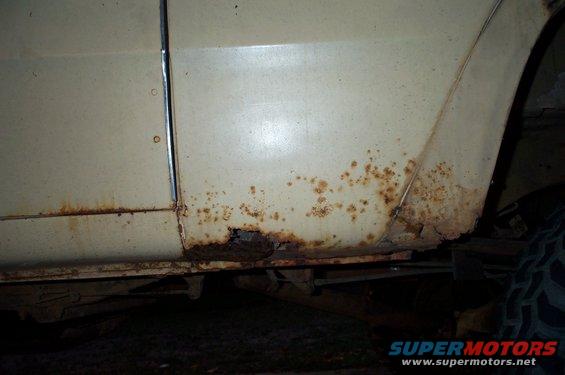 rusted lower body panel with visible holes and corrosion