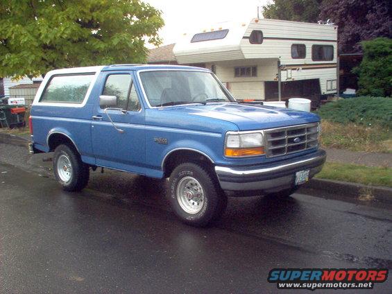 Blue 1992 Ford Bronco parked on wet street, 3q-front view