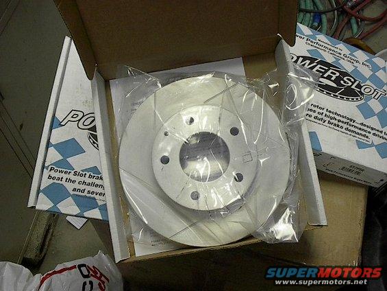 New Power Slot brake rotor in plastic wrap, inside its box with documentation