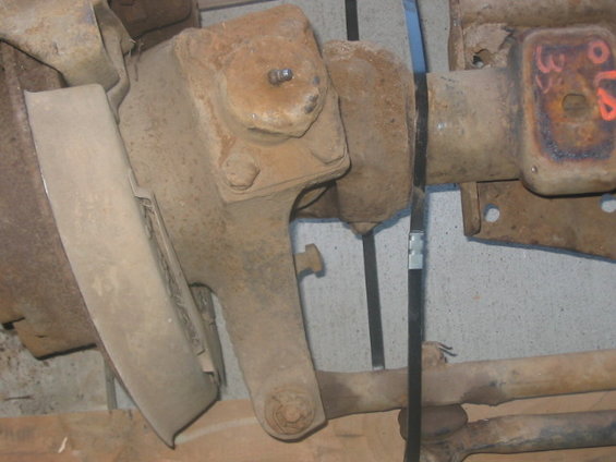 close-up of rusty axle housing with some suspension parts attached. Some orange markings are visible on a metal tag
