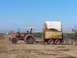 1979 Ford Bronco - Tractor and trailer working in a field under a clear blue sky.