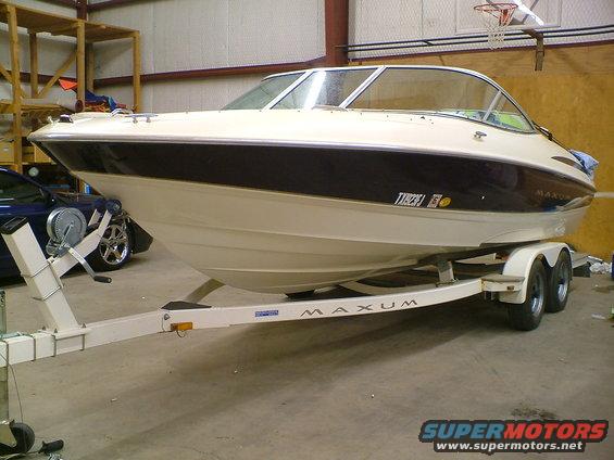 Maxum boat on a trailer in a garage, with a blue car visible to the left