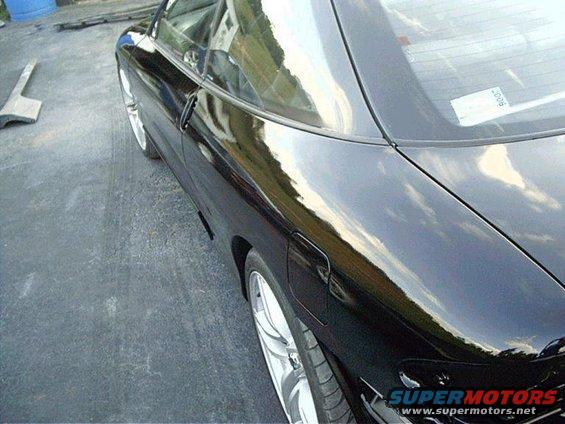 Black car side view, showing rear quarter panel and wheel