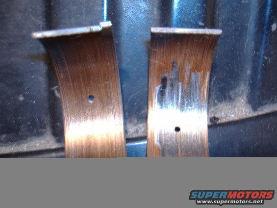 Close-up of two worn engine bearing shells with oil holes