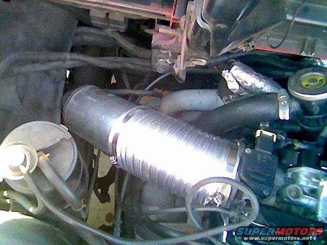 1986 Pontiac Fiero engine bay with silver intake tube and black hoses