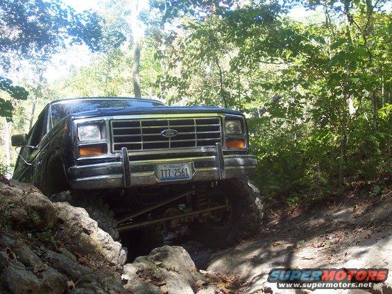 Ford Bronco navigating a rocky, wooded trail