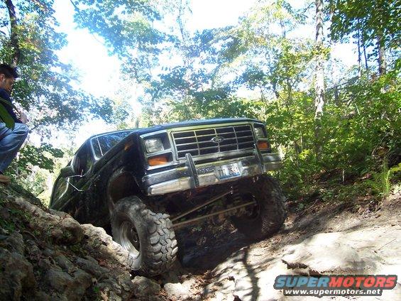 Black Ford Bronco with lifted suspension navigating a steep, rocky incline