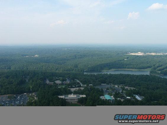 Overhead view of a wooded area with buildings and a parking lot visible