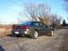 1996 Ford Probe - A dark gray 1996 Ford Probe is parked on a cracked asphalt road, with bare trees and a house in the background.