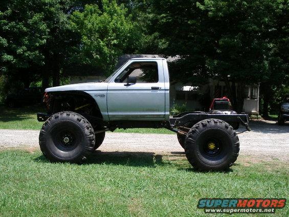 Side view of a custom lifted truck with oversized tires and a shortened bed