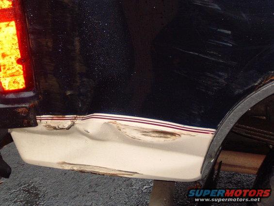 1993 Ford Bronco rear quarter panel with dent and rust, showing two-tone paint with red and white stripes