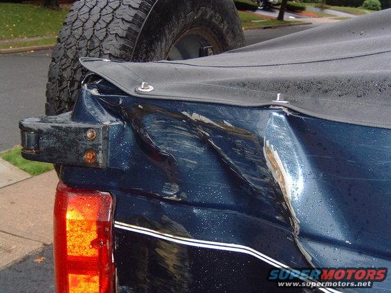 Rear of dark blue SUV with significant damage to the quarter panel and a spare tire mounted externally