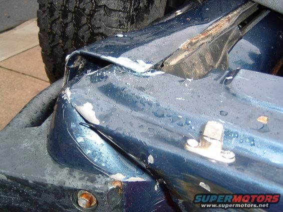 Damaged blue 1993 Ford Bronco fender with visible rust and tire tread