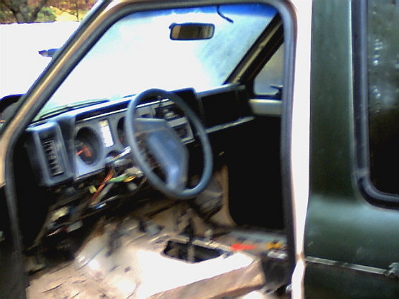 Interior of a 1987 Ford Bronco II with exposed wiring and removed floor panels