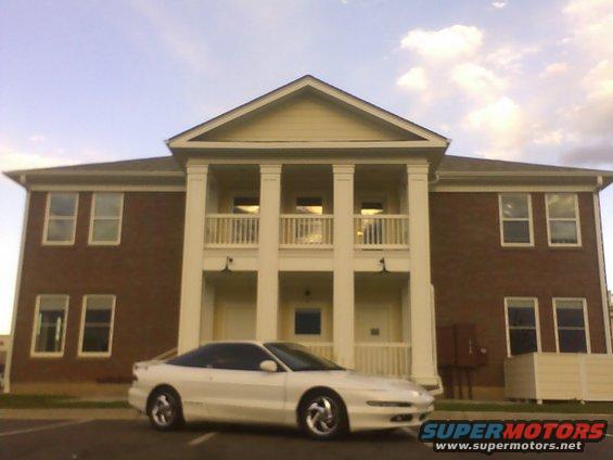 White 1996 Ford Probe parked in front of a two-story brick building with white columns