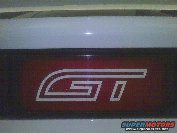 White GT emblem on a red panel. Supermotors.net watermark visible